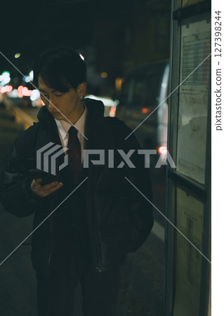 一名穿著西裝的年輕人正在等公車 127398244