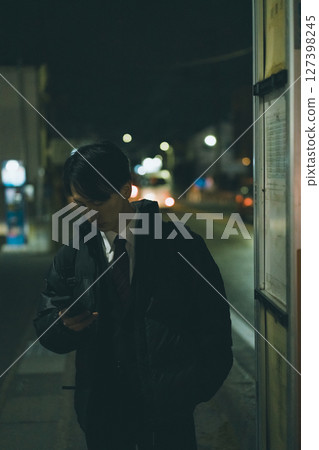 一名穿著西裝的年輕人正在等公車 127398245