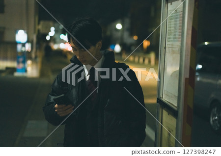 A young man in a suit waiting for a bus A young man in a suit waiting for a bus 127398247