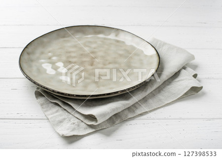 An empty grey textured plate on a white wooden table An empty grey textured plate on a white wooden table 127398533