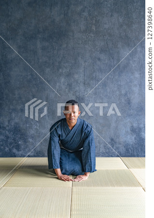 A black man wearing a yukata sitting on a tatami mat 127398640