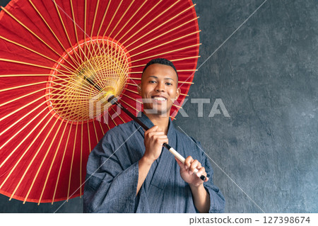 A black man wearing a yukata and holding a Japanese umbrella A black man wearing a yukata and holding a Japanese umbrella 127398674
