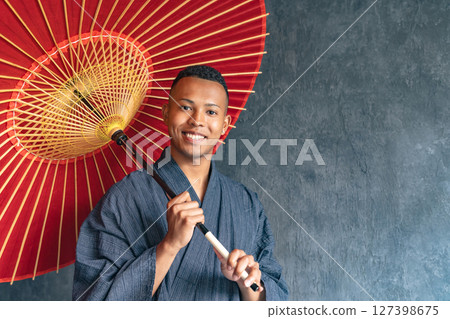 A black man wearing a yukata and holding a Japanese umbrella 127398675
