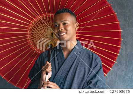 A black man wearing a yukata and holding a Japanese umbrella 127398676