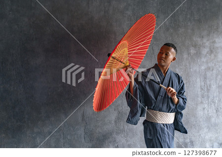 A black man wearing a yukata and holding a Japanese umbrella 127398677