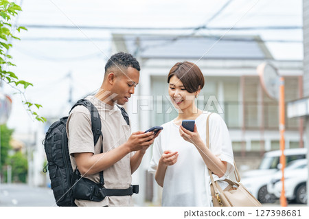 一名日本女性正在使用智慧型手機翻譯應用程式與一名黑人男子交談 127398681