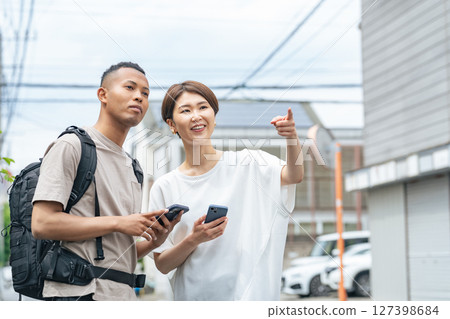 一名日本女子用智慧型手機給一名黑人男子指路 一名日本女子用智慧型手機給一名黑人男子指路 127398684