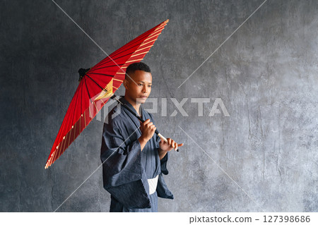 A black man wearing a yukata and holding a Japanese umbrella 127398686