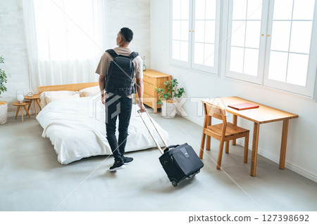 Black male traveler standing with suitcase in hotel room 127398692