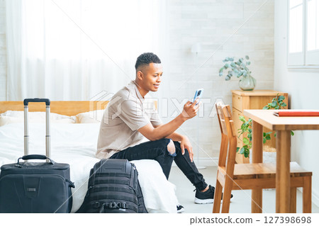 Black male traveler looking at smartphone in hotel room 127398698