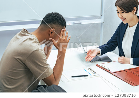 A Japanese female staff member interviewing a troubled black man A Japanese female staff member interviewing a troubled black man 127398716