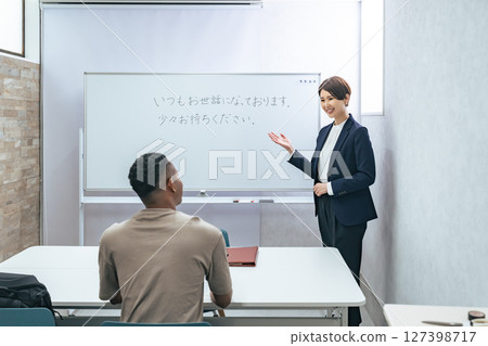 A female teacher teaches business terms to a black man at a Japanese language school A female teacher teaches business terms to a black man at a Japanese language school 127398717