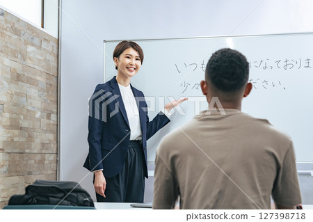 A female teacher teaches business terms to a black man at a Japanese language school A female teacher teaches business terms to a black man at a Japanese language school 127398718