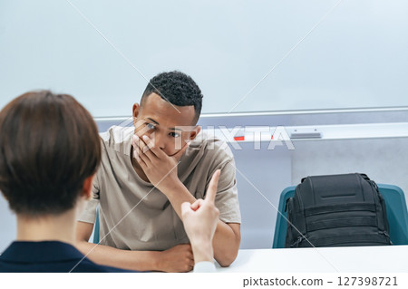 A Japanese female staff member interviewing a troubled black man A Japanese female staff member interviewing a troubled black man 127398721