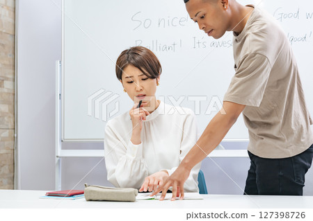 A black man and a Japanese woman having a conversation in a classroom A black man and a Japanese woman having a conversation in a classroom 127398726