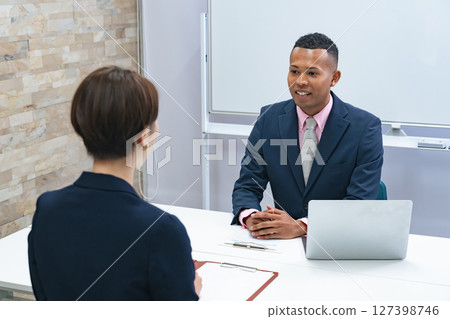 A Japanese female staff member interviewing a black male businessman A Japanese female staff member interviewing a black male businessman 127398746