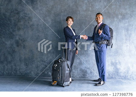 一名黑人男性商人和一名日本女性工作人員拿著旅行行李握手 一名黑人男性商人和一名日本女性工作人員拿著旅行行李握手 127398776