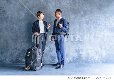 A black male businessman and a Japanese female staff member with travel luggage A black male businessman and a Japanese female staff member with travel luggage 127398777