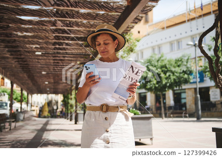 Woman Exploring a Historic Town While Using a Smartphone and Carrying a Map Woman Exploring a Historic Town While Using a Smartphone and Carrying a Map 127399426