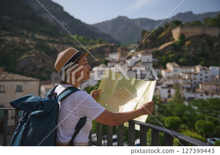 Woman Tourist Exploring a Scenic Town With a Map Amidst Mountainous Landscape 127399443