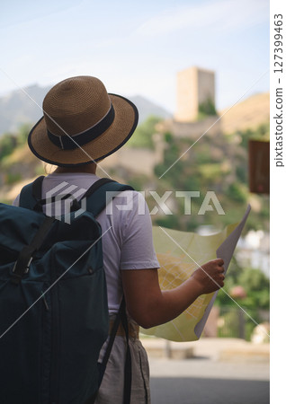 Female Tourist Exploring Scenic Outdoor Townscape With a Map and Backpack 127399463