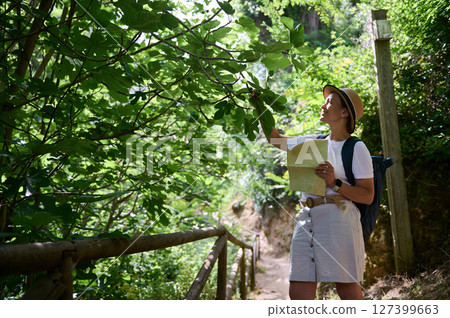 Woman Exploring a Sunlit Forest Trail with a Map in Hand Woman Exploring a Sunlit Forest Trail with a Map in Hand 127399663