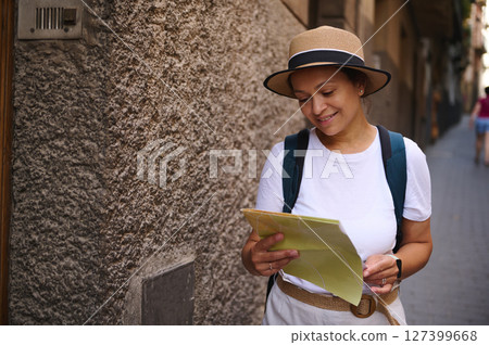 Smiling Woman Tourist Exploring a Historic City Holding a Paper Map 127399668