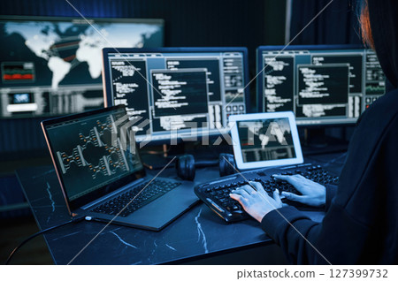Information on screens. Young professional female hacker is indoors by computer with lot of information on displays Information on screens. Young professional female hacker is indoors by computer with lot of information on displays 127399732