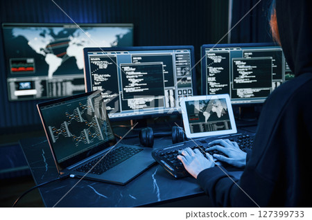 Information on screens. Young professional female hacker is indoors by computer with lot of information on displays Information on screens. Young professional female hacker is indoors by computer with lot of information on displays 127399733