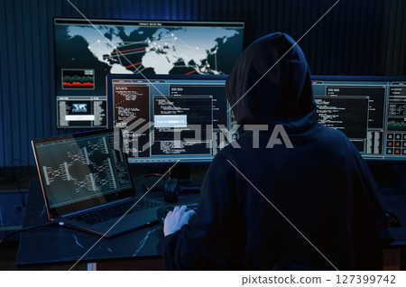 Dark room. Young professional female hacker is indoors by computer with lot of information on displays Dark room. Young professional female hacker is indoors by computer with lot of information on displays 127399742