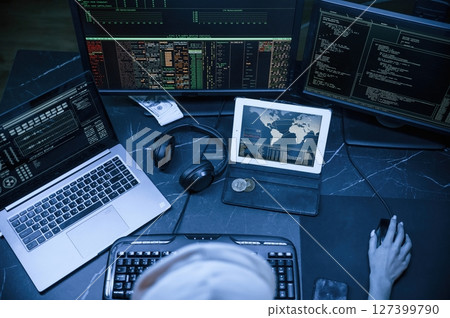 Top view. Young professional female hacker is indoors by computer with lot of information on displays Top view. Young professional female hacker is indoors by computer with lot of information on displays 127399790