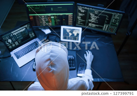 Top view. Young professional female hacker is indoors by computer with lot of information on displays Top view. Young professional female hacker is indoors by computer with lot of information on displays 127399791