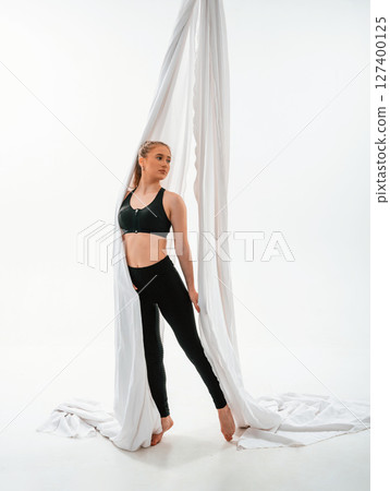 Standing and posing. Young beautiful woman doing fly yoga against white background Standing and posing. Young beautiful woman doing fly yoga against white background 127400125