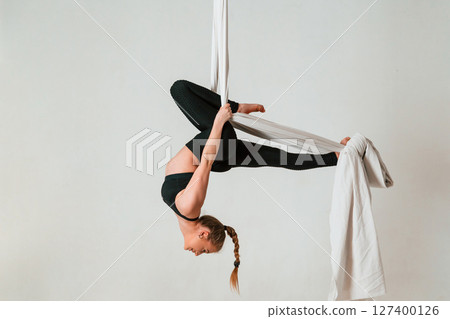 In the midair. Young beautiful woman doing fly yoga against white background In the midair. Young beautiful woman doing fly yoga against white background 127400126