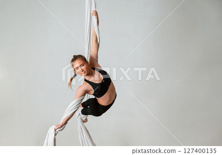 Professional occupation. Young beautiful woman doing fly yoga against white background 127400135