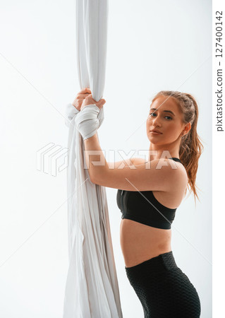 Beautiful woman is standing and holding the canvas. Conception of fly yoga. Against white background Beautiful woman is standing and holding the canvas. Conception of fly yoga. Against white background 127400142