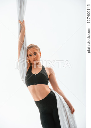 Beautiful woman is standing and holding the canvas. Conception of fly yoga. Against white background 127400143