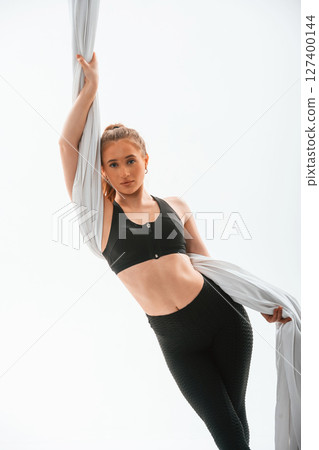 Beautiful woman is standing and holding the canvas. Conception of fly yoga. Against white background Beautiful woman is standing and holding the canvas. Conception of fly yoga. Against white background 127400144