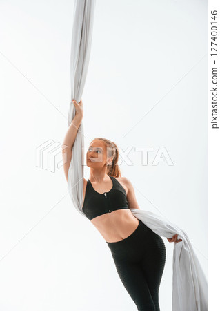Beautiful woman is standing and holding the canvas. Conception of fly yoga. Against white background Beautiful woman is standing and holding the canvas. Conception of fly yoga. Against white background 127400146