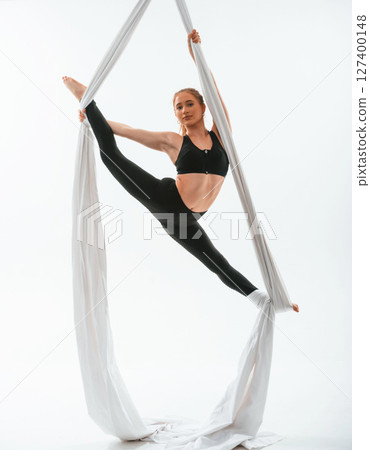Conception of flexibility. Young beautiful woman doing fly yoga against white background 127400148