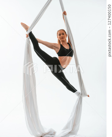 Conception of flexibility. Young beautiful woman doing fly yoga against white background Conception of flexibility. Young beautiful woman doing fly yoga against white background 127400150