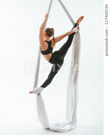 Conception of flexibility. Young beautiful woman doing fly yoga against white background Conception of flexibility. Young beautiful woman doing fly yoga against white background 127400156