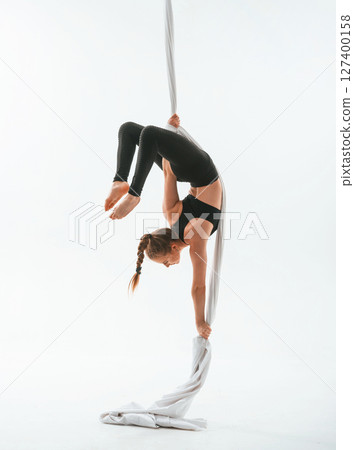 Flexible body type. Young beautiful woman doing fly yoga against white background Flexible body type. Young beautiful woman doing fly yoga against white background 127400158