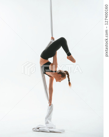 Stretching exercises. Young beautiful woman doing fly yoga against white background Stretching exercises. Young beautiful woman doing fly yoga against white background 127400160