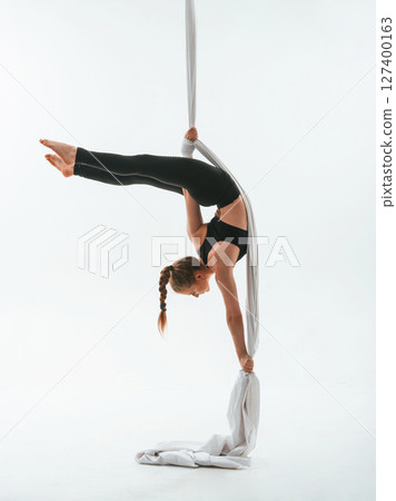 Stretching exercises. Young beautiful woman doing fly yoga against white background Stretching exercises. Young beautiful woman doing fly yoga against white background 127400163