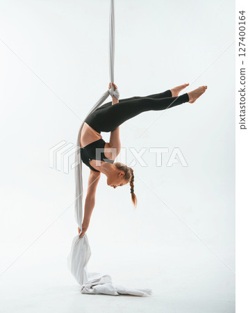 Stretching exercises. Young beautiful woman doing fly yoga against white background Stretching exercises. Young beautiful woman doing fly yoga against white background 127400164