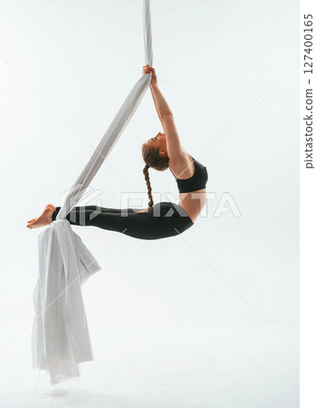 Stretching exercises. Young beautiful woman doing fly yoga against white background Stretching exercises. Young beautiful woman doing fly yoga against white background 127400165