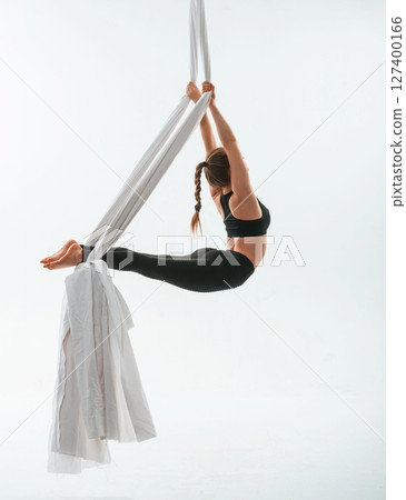 Flexible body type. Young beautiful woman doing fly yoga against white background 127400166