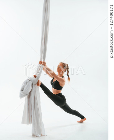 Flexible body type. Young beautiful woman doing fly yoga against white background 127400171