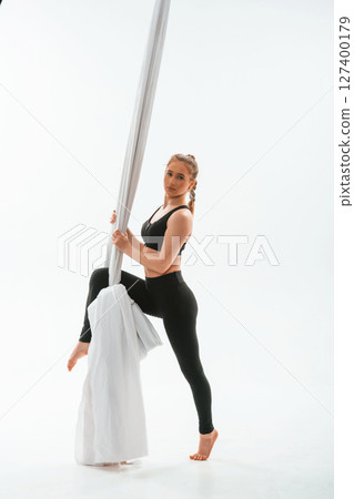 Front view, standing and posing. Young beautiful woman doing fly yoga against white background 127400179